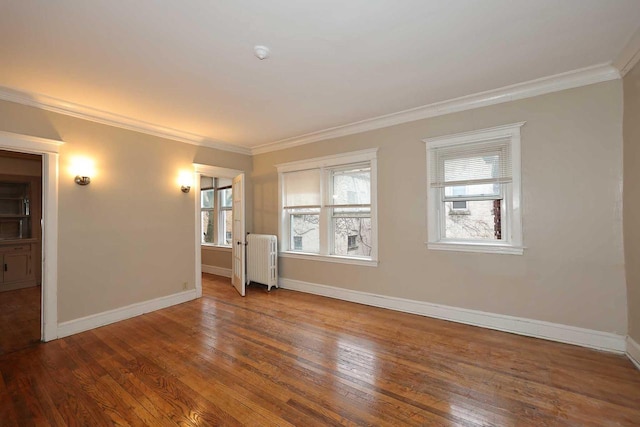 spare room featuring hardwood / wood-style floors, ornamental molding, baseboards, and radiator