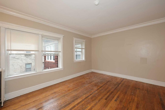 empty room with wood-type flooring, crown molding, and baseboards
