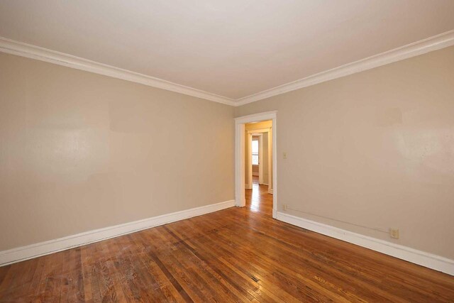 empty room with baseboards, crown molding, and hardwood / wood-style flooring