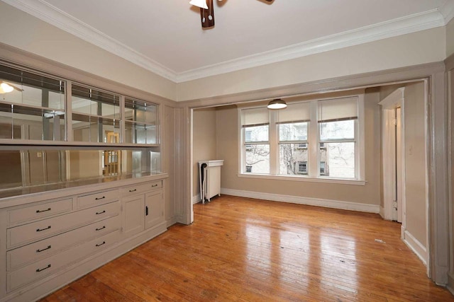 interior space with baseboards, light wood-style flooring, ceiling fan, and ornamental molding