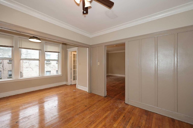 empty room with baseboards, crown molding, ceiling fan, and hardwood / wood-style floors