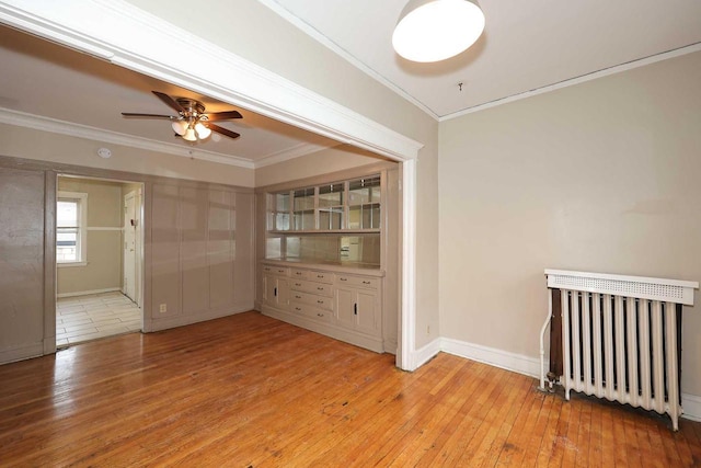 spare room featuring radiator heating unit, light wood-style floors, and crown molding