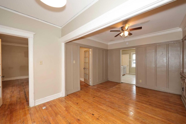 spare room with light wood-type flooring, crown molding, baseboards, and ceiling fan