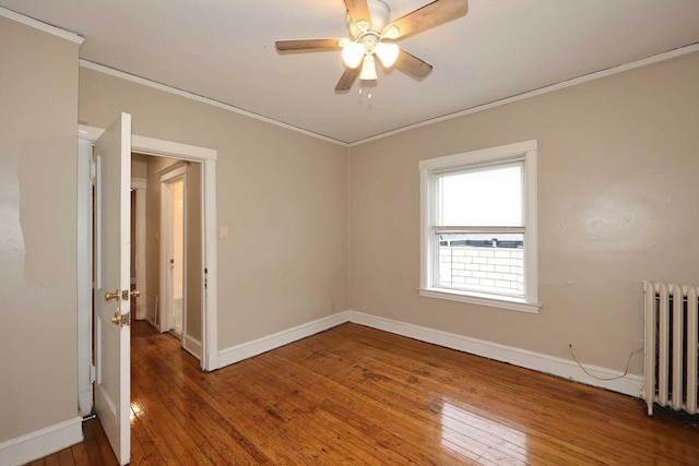 empty room with hardwood / wood-style flooring, radiator, and crown molding