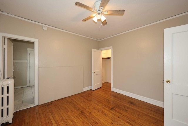 unfurnished bedroom with crown molding, radiator heating unit, and hardwood / wood-style floors