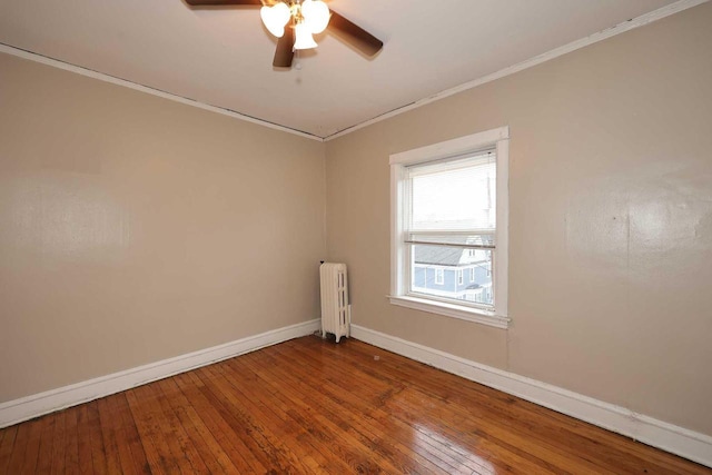 spare room featuring baseboards, crown molding, radiator heating unit, and hardwood / wood-style flooring