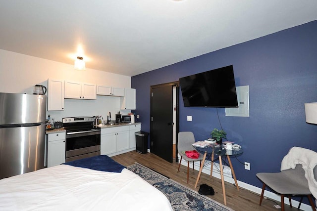 bedroom featuring baseboards, dark wood-style flooring, a sink, and freestanding refrigerator