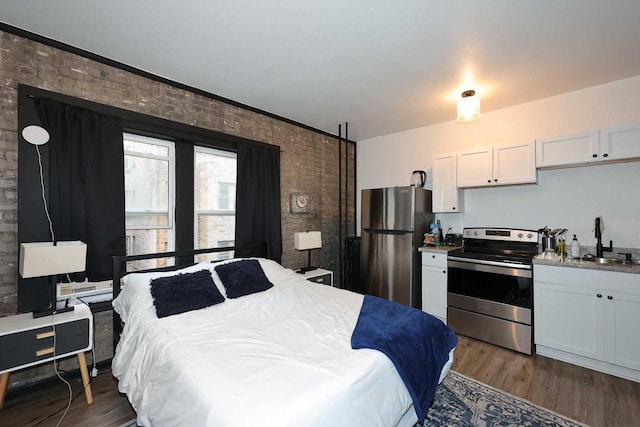 kitchen with white cabinetry, stainless steel appliances, dark wood finished floors, a sink, and brick wall