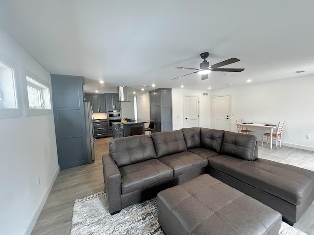 living room featuring recessed lighting, baseboards, a ceiling fan, and light wood-style floors