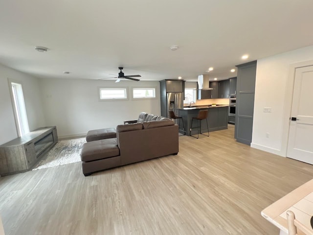 living area with recessed lighting, light wood-style floors, baseboards, and a ceiling fan