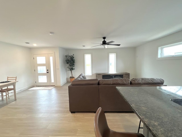 living area featuring baseboards, a ceiling fan, and light wood-style floors