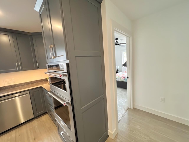 kitchen with stainless steel appliances, light wood-style flooring, baseboards, and gray cabinets