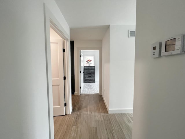 hallway featuring wood finished floors, baseboards, and visible vents