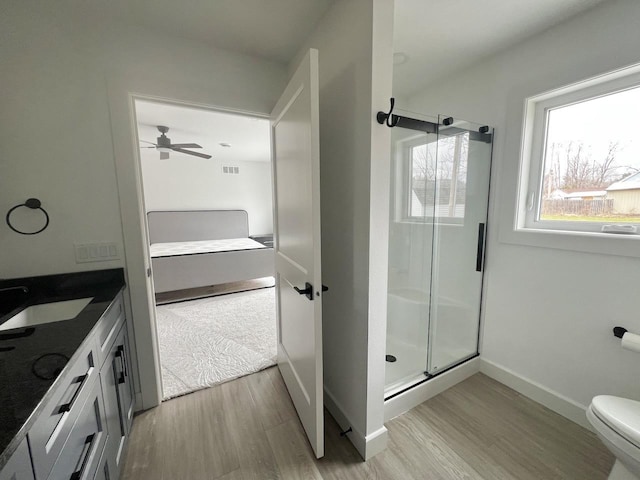 full bath featuring a shower stall, ceiling fan, toilet, and wood finished floors