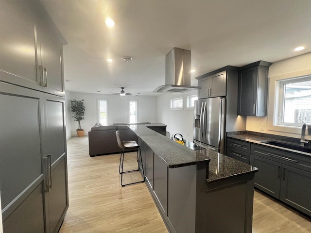 kitchen featuring stainless steel refrigerator with ice dispenser, a sink, open floor plan, a ceiling fan, and extractor fan