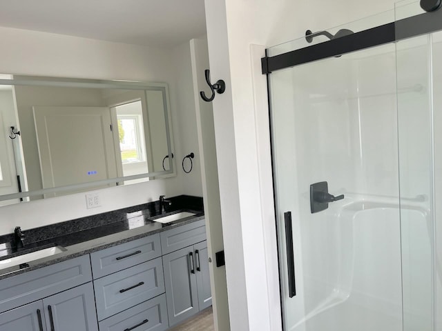 full bathroom with a sink, a walk in shower, and double vanity