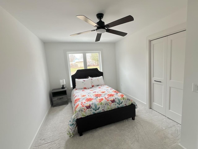 carpeted bedroom with a closet, baseboards, and ceiling fan