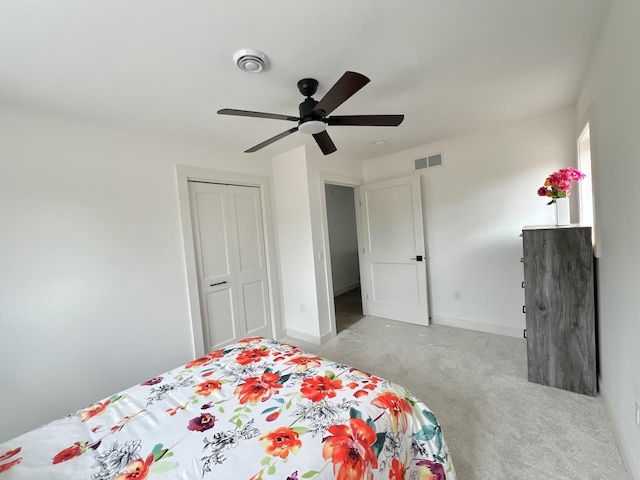 bedroom with a closet, baseboards, carpet flooring, a ceiling fan, and visible vents