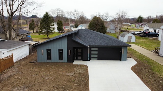 view of front of home featuring a residential view, driveway, fence, and an attached garage