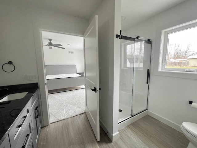 ensuite bathroom featuring a shower stall, ensuite bath, toilet, and wood finished floors