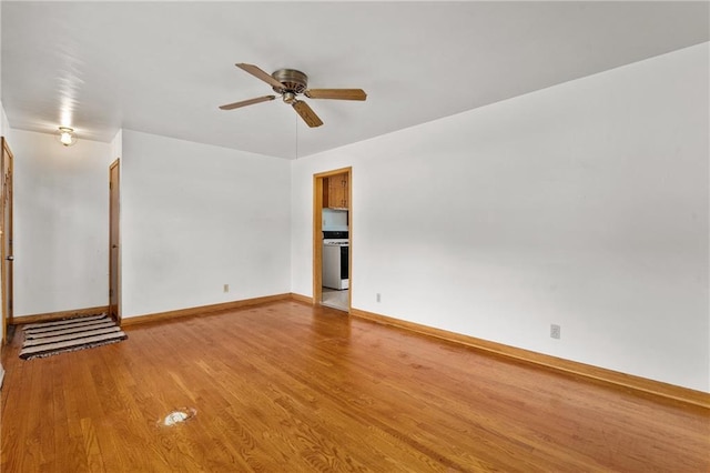 spare room with baseboards, light wood-style floors, and a ceiling fan