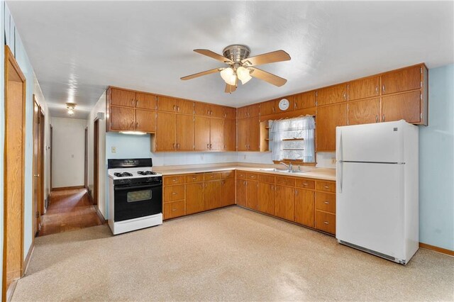 kitchen featuring light countertops, brown cabinets, range with gas stovetop, and freestanding refrigerator