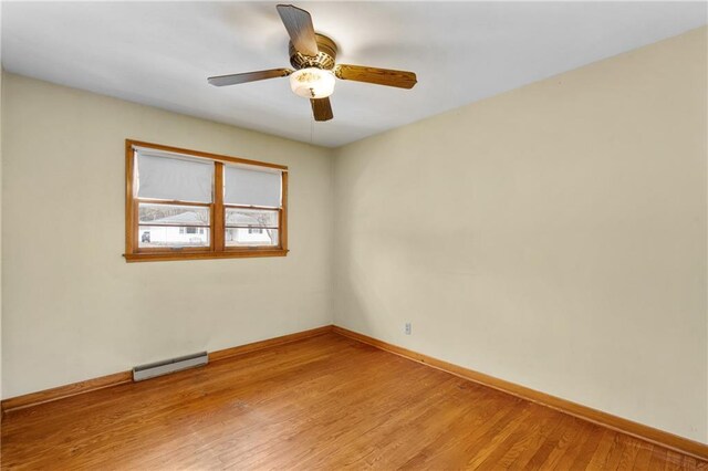 spare room with light wood finished floors, baseboards, a baseboard radiator, and a ceiling fan