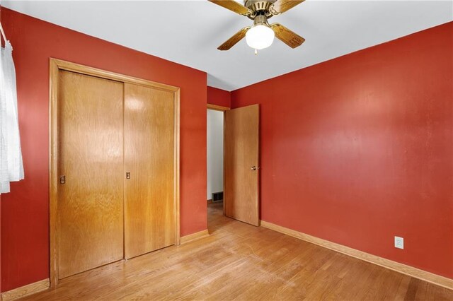 unfurnished bedroom with a closet, visible vents, baseboards, a ceiling fan, and light wood-style floors