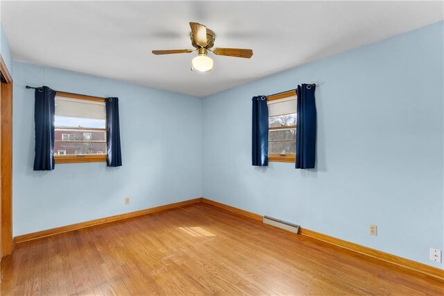 unfurnished room with a ceiling fan, wood finished floors, baseboards, and a wealth of natural light