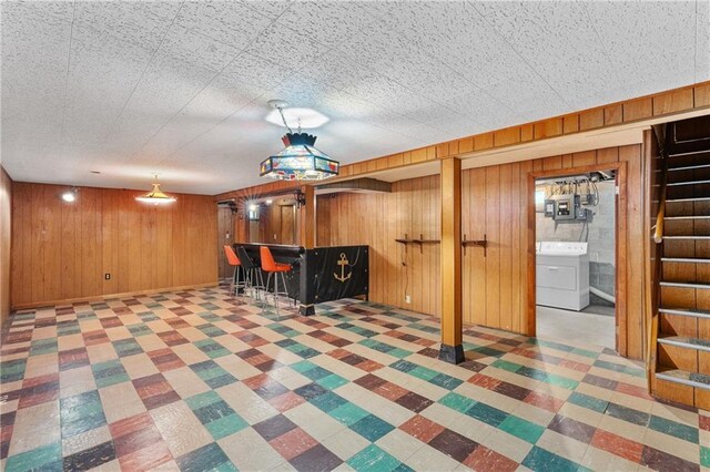 playroom featuring washer / clothes dryer, wood walls, and bar