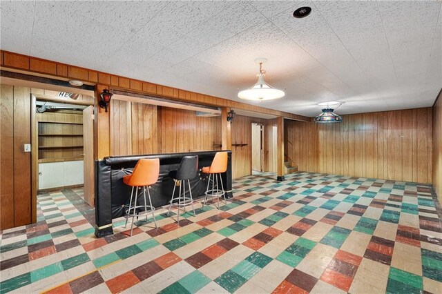 interior space with wooden walls, a dry bar, and stairway