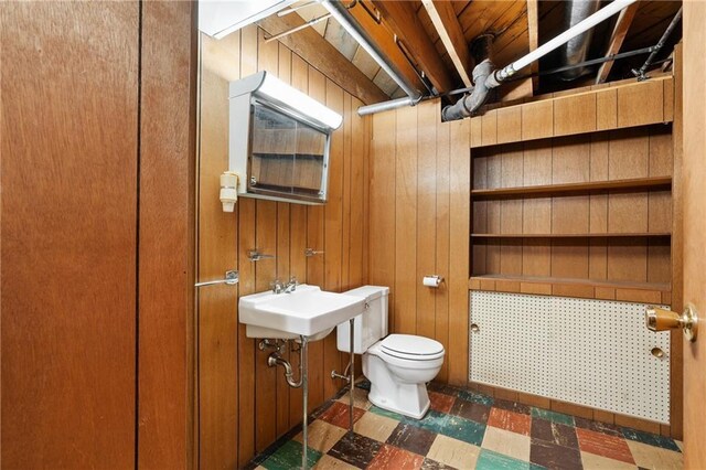 bathroom featuring tile patterned floors, toilet, wood walls, and a sink