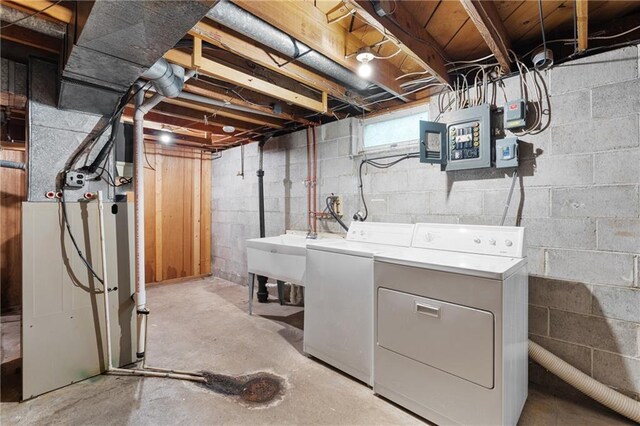 below grade area featuring washing machine and clothes dryer, a sink, and electric panel
