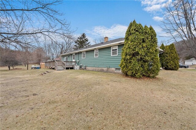 back of house featuring a lawn, a chimney, and a wooden deck