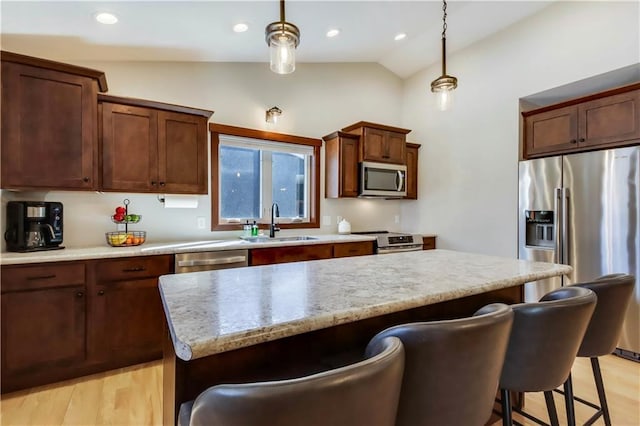 820 Rusty Ct, Altoona, WI 54720 - kitchen featuring appliances with stainless steel finishes, vaulted ceiling, a sink, a breakfast bar area, and light wood-style flooring