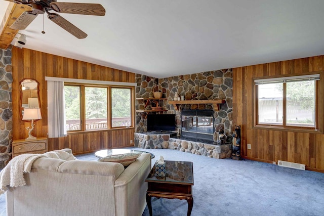 W5854 Bubbling Springs Dr, Elkhorn, WI 53121 - carpeted living room featuring visible vents, wood walls, ceiling fan, and a stone fireplace