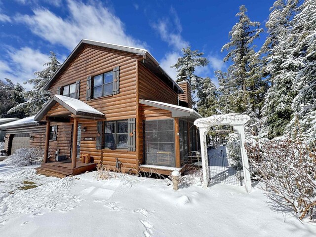 7118 Timber Ln, Rhinelander, WI 54501 - chalet / cabin featuring a sunroom, log veneer siding, an attached garage, and a chimney