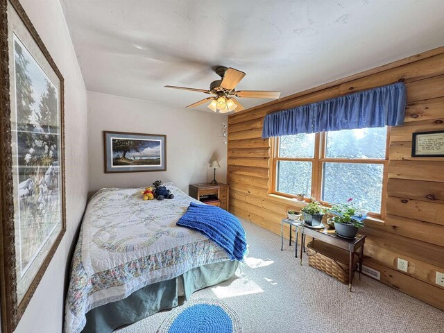 7118 Timber Ln, Rhinelander, WI 54501 - carpeted bedroom with ceiling fan and rustic walls