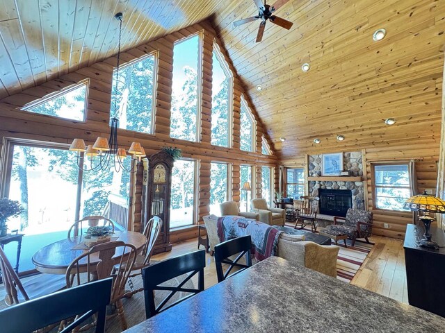 7118 Timber Ln, Rhinelander, WI 54501 - dining area with high vaulted ceiling, a stone fireplace, wood ceiling, hardwood / wood-style floors, and log walls