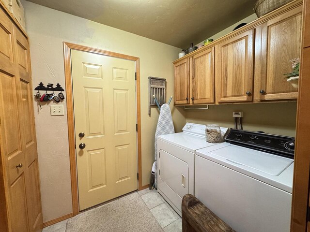 7118 Timber Ln, Rhinelander, WI 54501 - clothes washing area with light tile patterned floors, cabinet space, and washer and clothes dryer