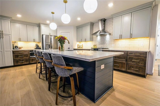 11684 Brook Ln, Hayward, WI 54843 - kitchen featuring a center island, light wood-style floors, wall chimney exhaust hood, stainless steel appliances, and a sink