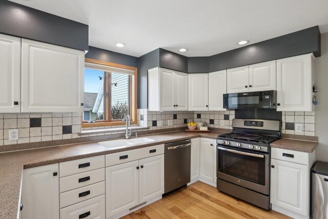 119 Vilas Hibbard Pkwy, Lodi, WI 53555 - kitchen featuring white cabinetry, tasteful backsplash, light wood-type flooring, a sink, and appliances with stainless steel finishes