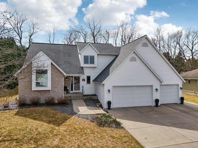 119 Vilas Hibbard Pkwy, Lodi, WI 53555 - view of front of property featuring an attached garage, brick siding, a front lawn, driveway, and a shingled roof
