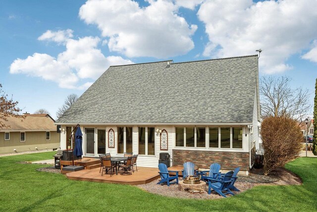 119 Vilas Hibbard Pkwy, Lodi, WI 53555 - back of house featuring stone siding, a wooden deck, an outdoor fire pit, a lawn, and a shingled roof