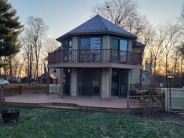 2215 N Shore Dr, Delavan, WI 53115 - back of property at dusk featuring a balcony, fence, and a yard