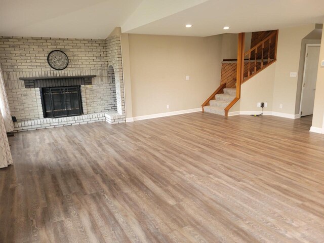 2215 N Shore Dr, Delavan, WI 53115 - unfurnished living room featuring stairs, recessed lighting, baseboards, a brick fireplace, and wood finished floors