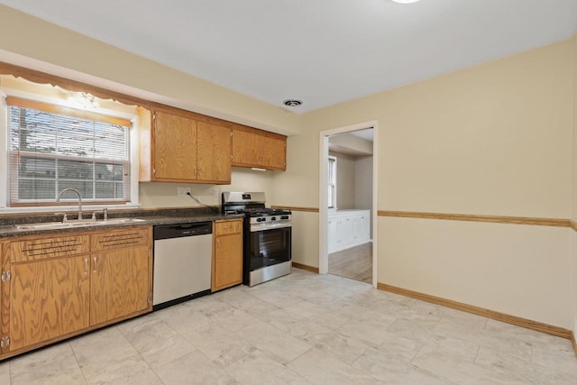 kitchen with dark countertops, visible vents, dishwashing machine, a sink, and stainless steel range with gas cooktop