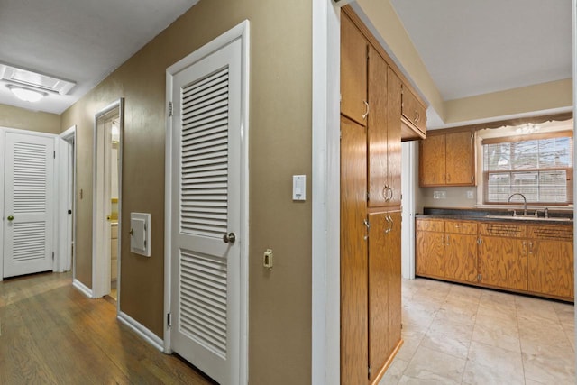 hall featuring baseboards and a sink