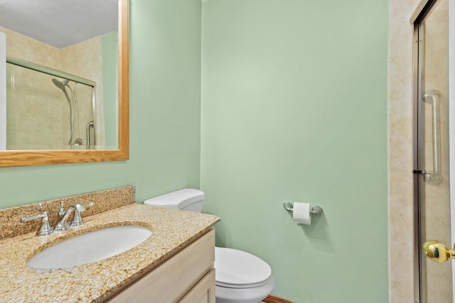 bathroom featuring toilet, vanity, and a stall shower