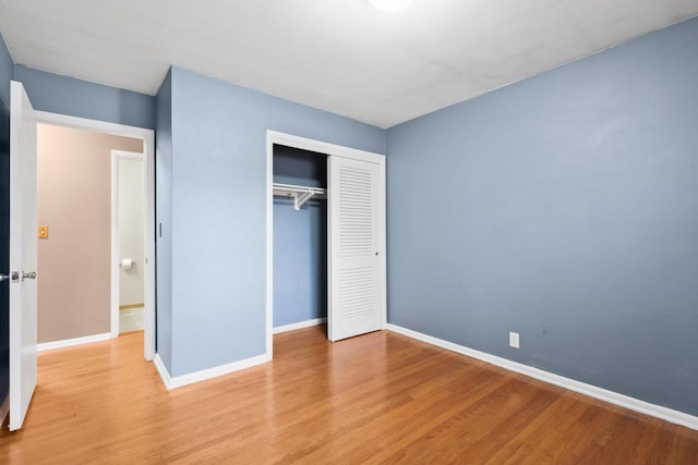 unfurnished bedroom with baseboards, a closet, and light wood-type flooring